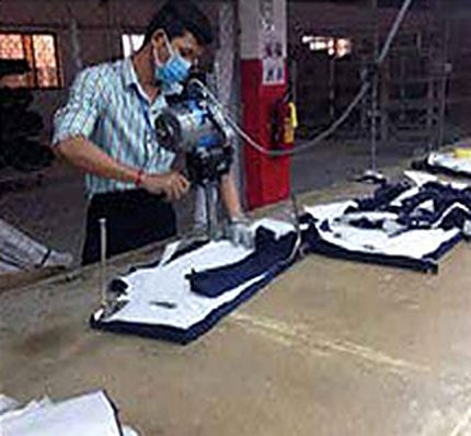 Worker cutting denim pattern pieces with a band knife